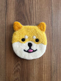 Felted dog coaster on a wooden surface