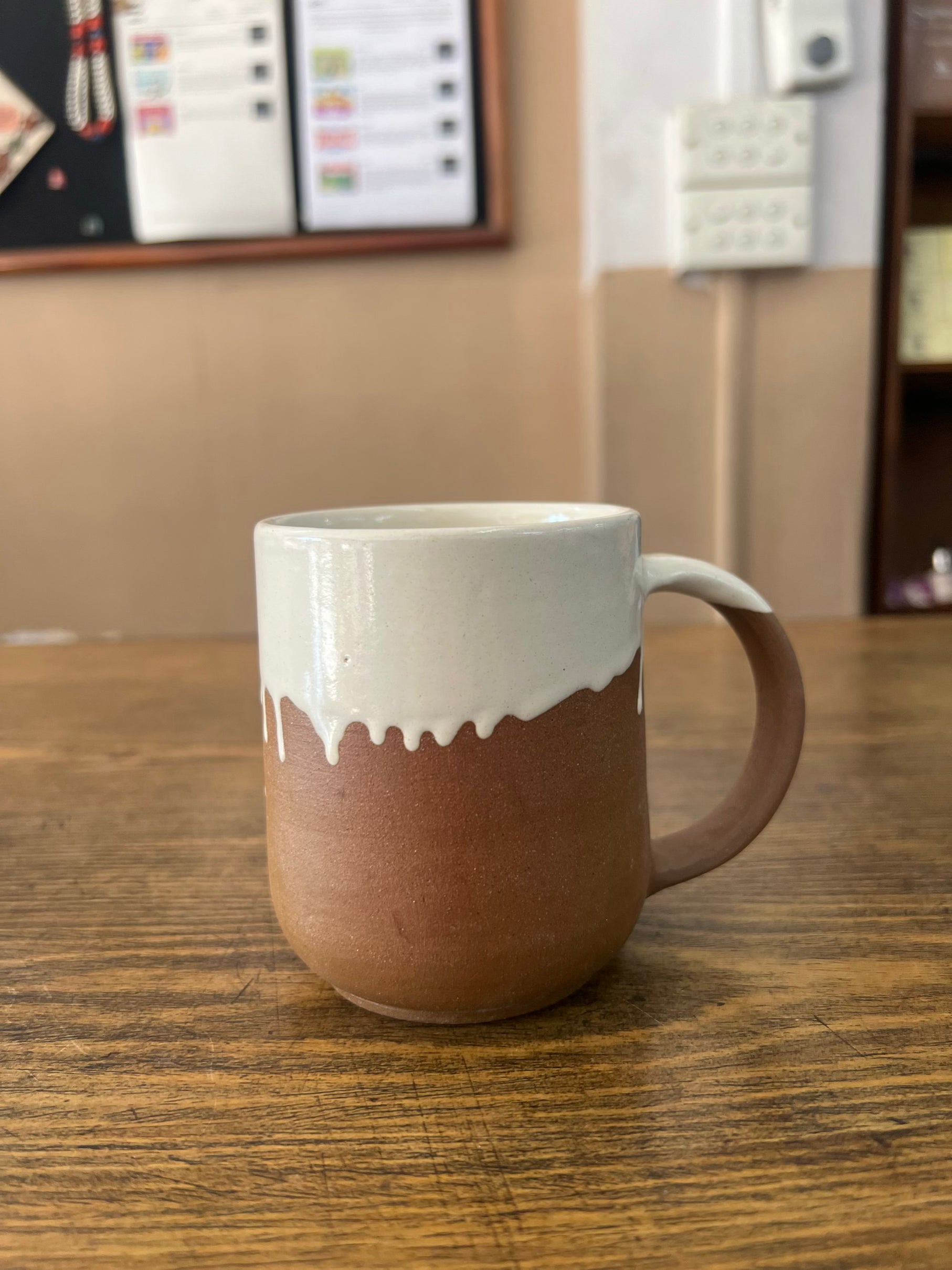 Two-tone ceramic mug on a wooden surface with a neutral background