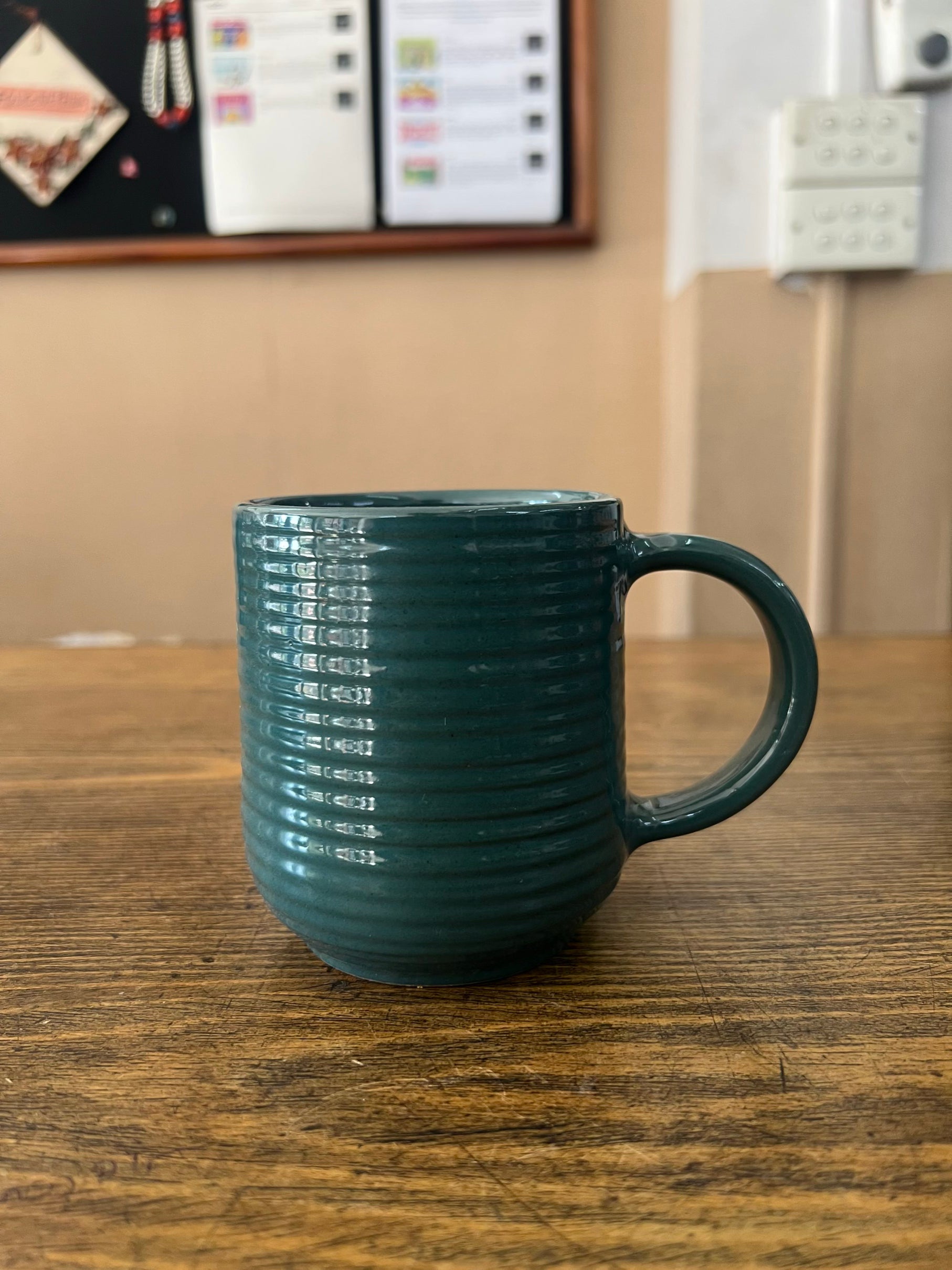 Green mug on a wooden surface with a blurred background