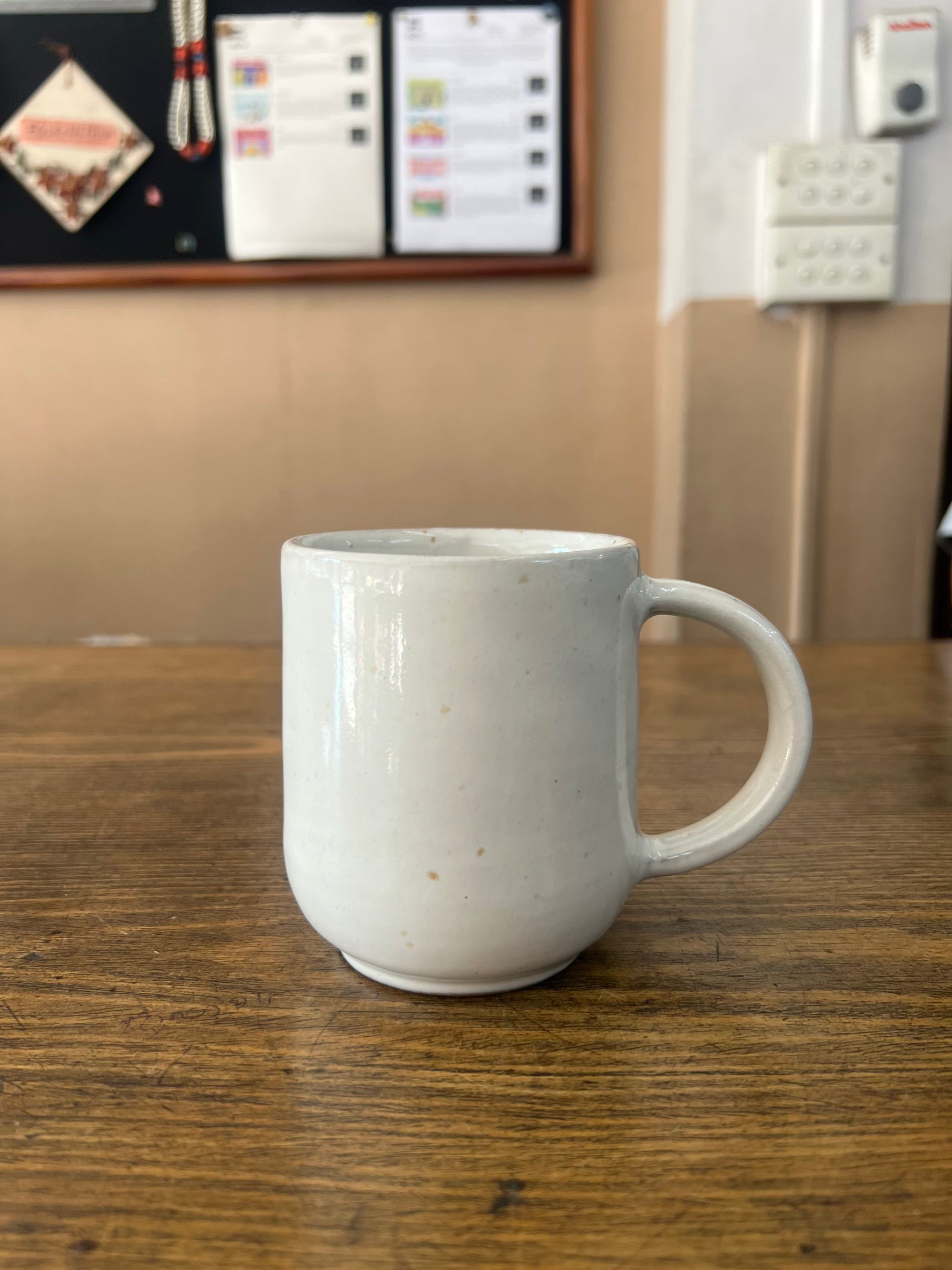 White ceramic mug on a wooden surface with a blurred background
