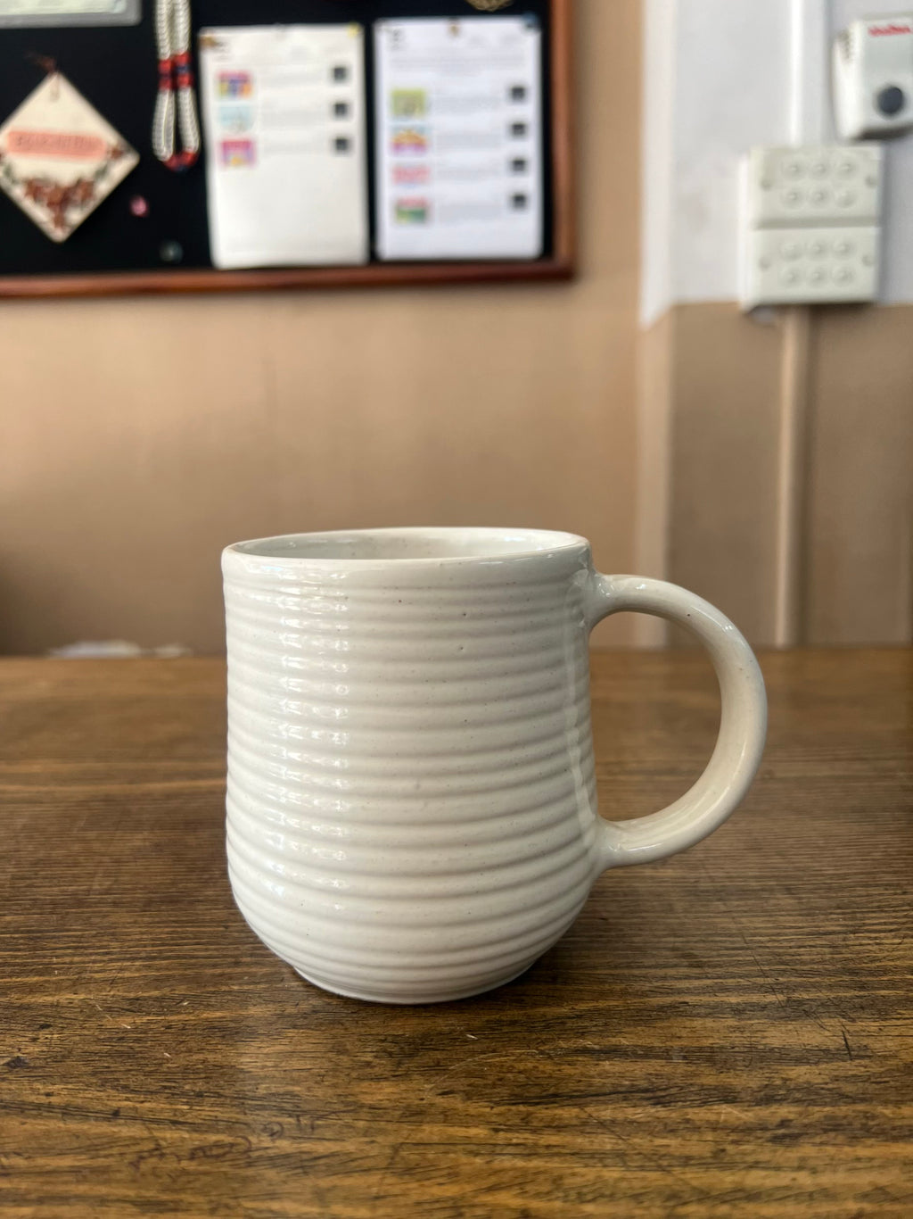 White ceramic mug on a wooden surface with a blurred background