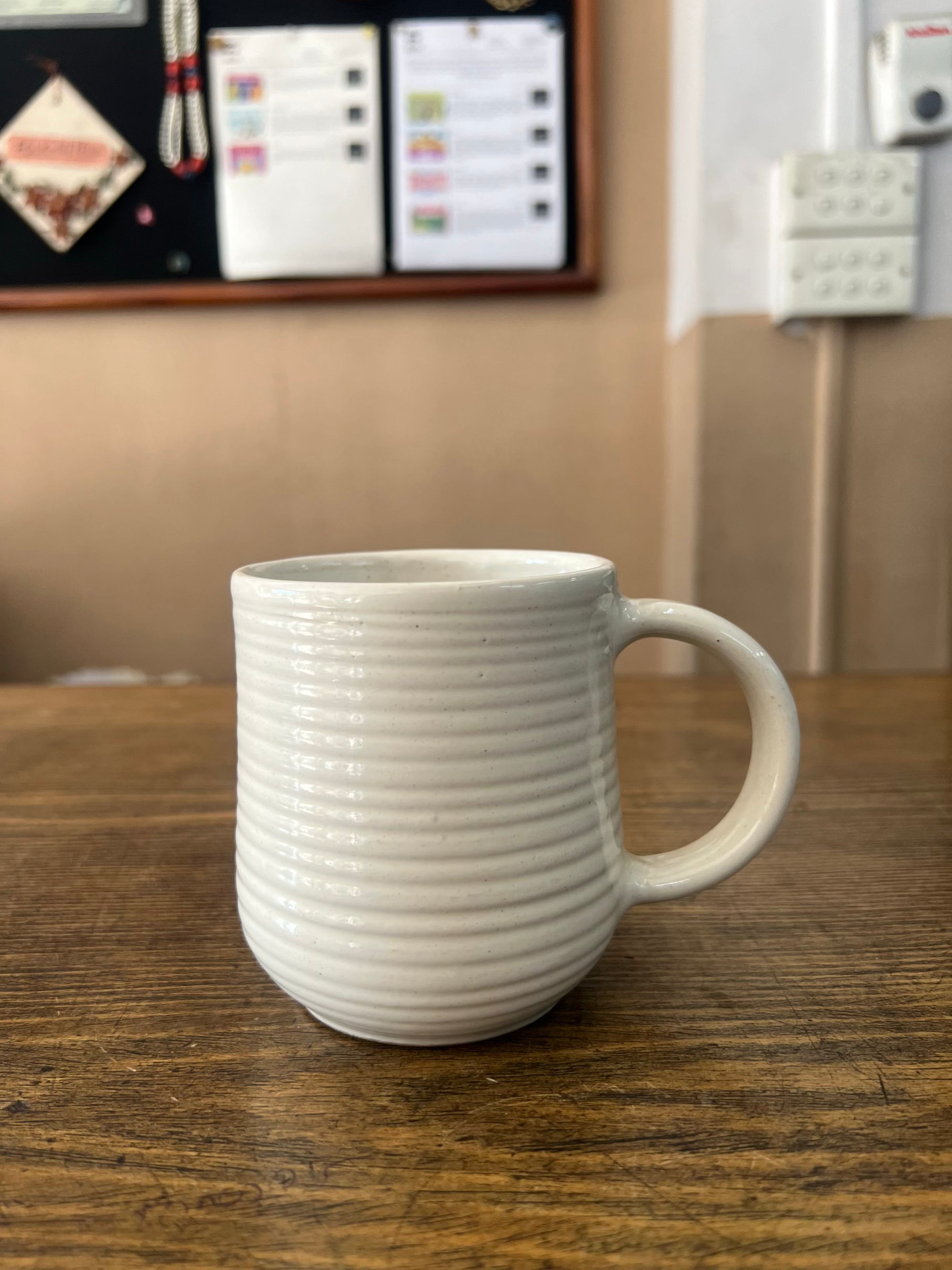 White ceramic mug on a wooden surface with a blurred background