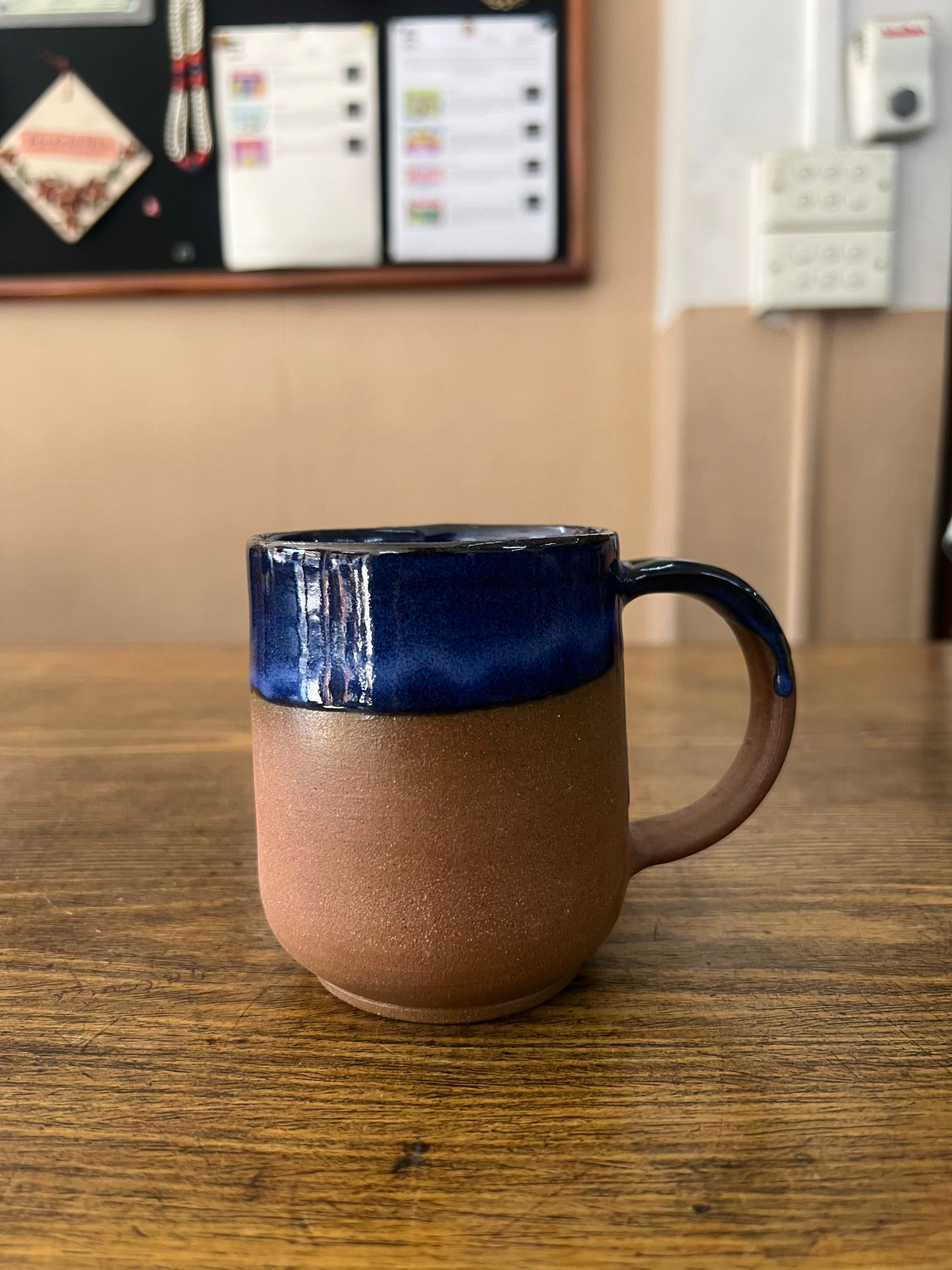Ceramic mug with blue top and brown bottom on a wooden surface